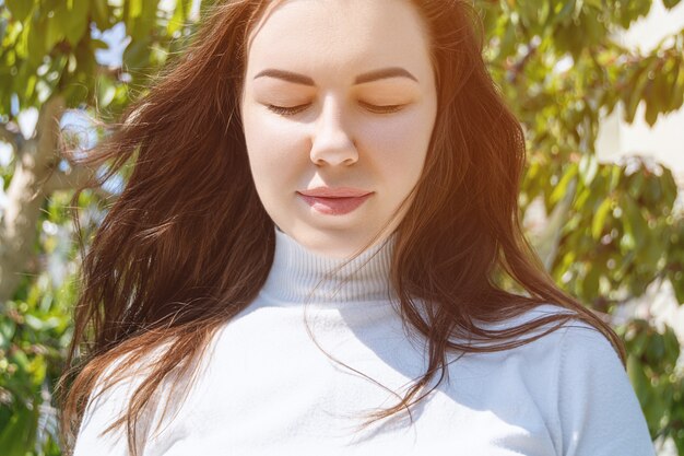 Portrait of young caucasian attractive female with closed eyes on a floral background