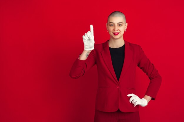 Portrait of young caucasian bald woman on red wall