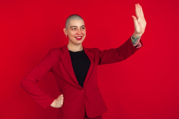 Portrait of young caucasian bald woman on red wall