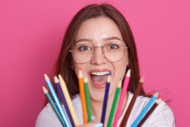 Portrait of young caucasian girl with straight hair holding colored pencils