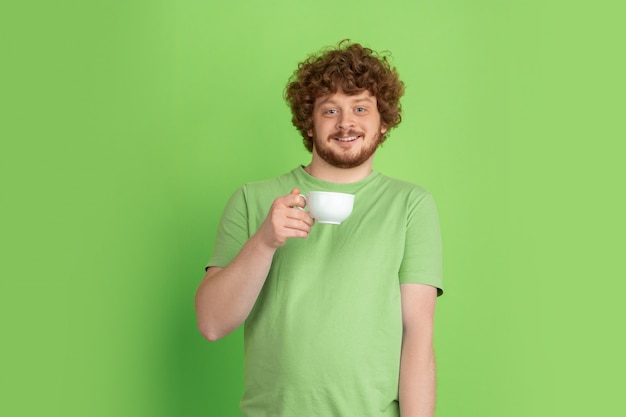 Portrait of young caucasian man with bright emotions on green studio