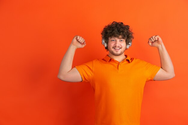 Portrait of young caucasian man with bright emotions on orange studio