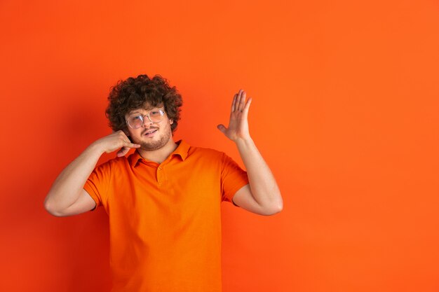 Portrait of young caucasian man with bright emotions on orange studio