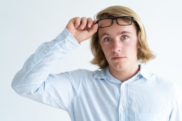 Portrait of young Caucasian student raising glasses in surprise