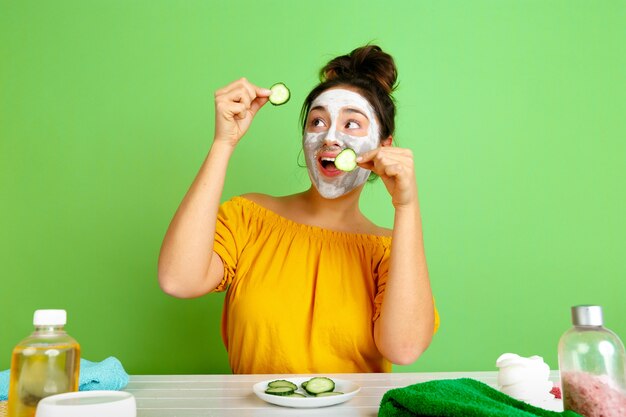 Portrait of young caucasian woman in her beauty day, skin and hair care routine. Female model with natural cosmetics applying facial mask for make up. Body and face care, natural beauty concept.