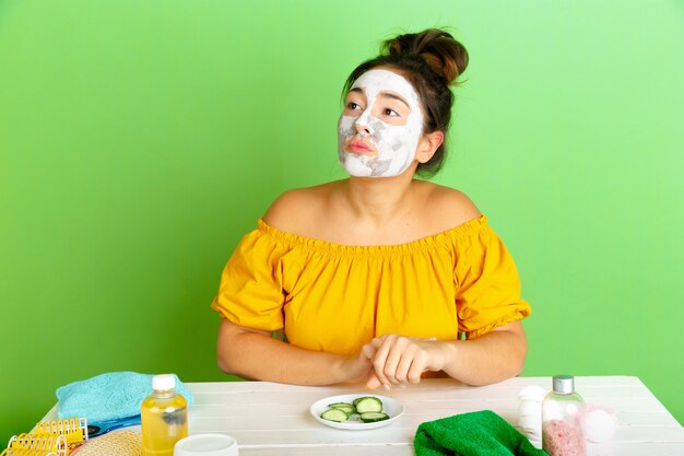 Portrait of young caucasian woman in her beauty day, skin and hair care routine. Female model with natural cosmetics applying facial mask for make up. Body and face care, natural beauty concept.