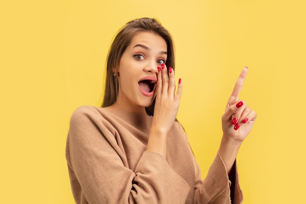 Portrait of young caucasian woman with bright emotions isolated on yellow