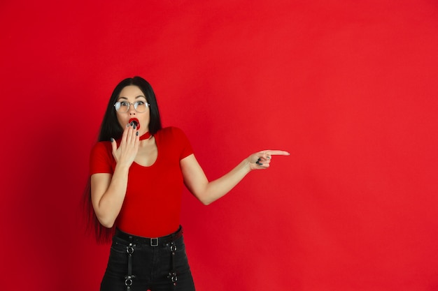 Portrait of young caucasian woman with bright emotions on red studio background