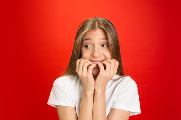 Free photo portrait of young caucasian woman with bright emotions on red studio