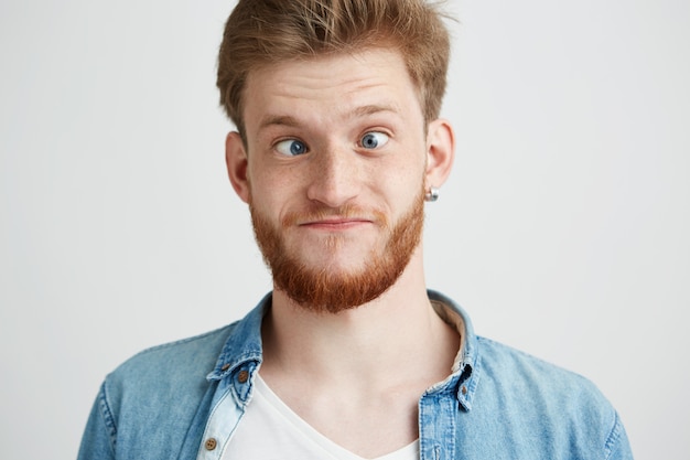 Portrait of young cheerful merry guy making funny face fooling.