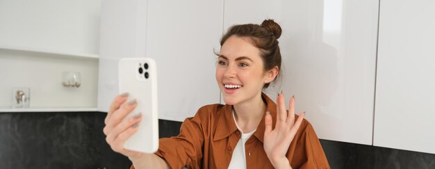 Free photo portrait of young cheerful woman laughing and smiling during phone call video chats with friend sits