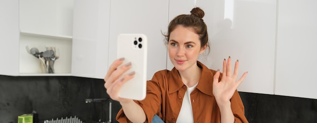 Free photo portrait of young cheerful woman laughing and smiling during phone call video chats with friend sits