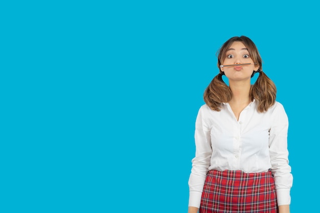 Free photo portrait of young college girl making mustache with pen. high quality photo