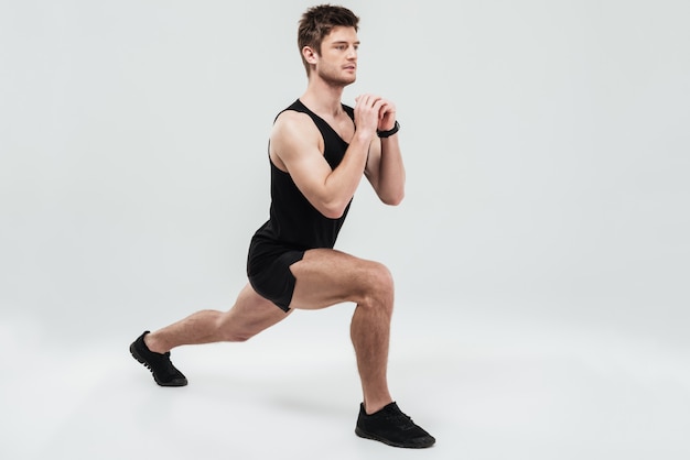 Portrait of a young concentrated man doing squats exercise