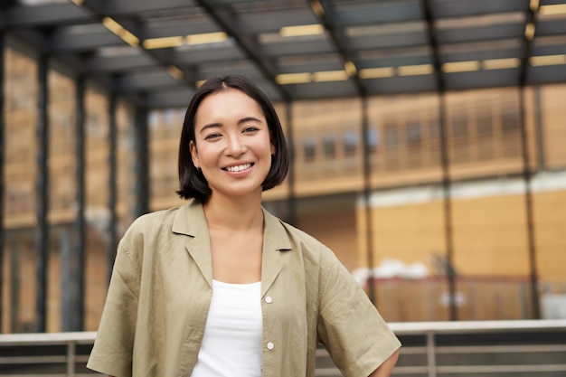 Portrait of young confident female model girl in casual clothes posing outside near glass building s