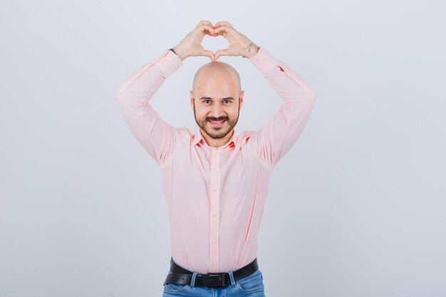 Portrait of a young confident man showing heart gesture
