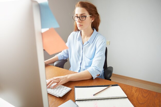 Portrait of young confident woman entrepreneur typing on the laptop