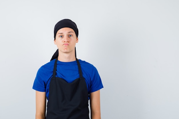 Free photo portrait of young cook man posing while standing in t-shirt, apron and looking hesitant front view