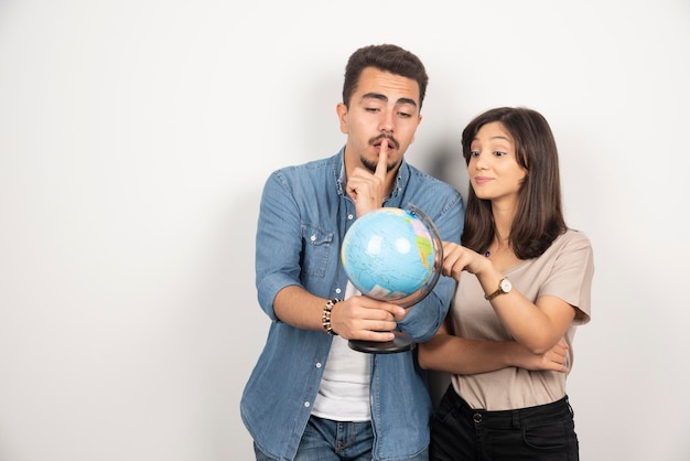 Portrait of young couple holding map globe.