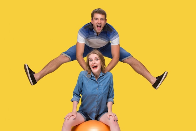 Free photo portrait of a young couple jumping against yellow wall