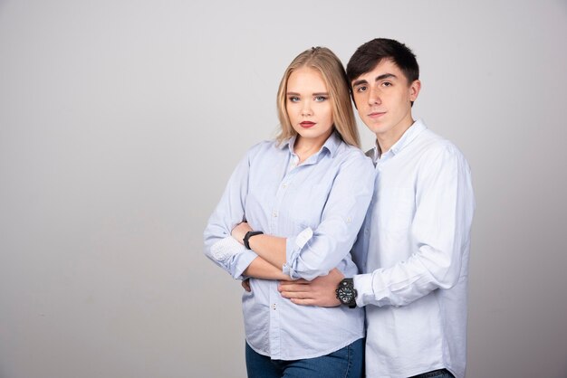 Portrait of young couple looking against gray wall.