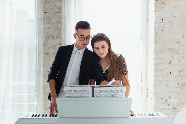 Portrait of a young couple looking at musical sheet learning to play the piano