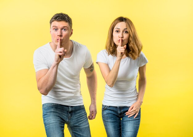 Portrait of a young couple making silence gesture by keeping finger over her lips