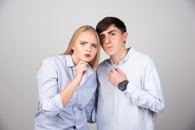 Portrait of a young couple posing on gray wall.