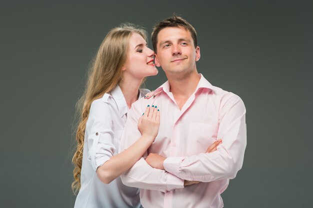 Portrait of a young couple standing against gray background