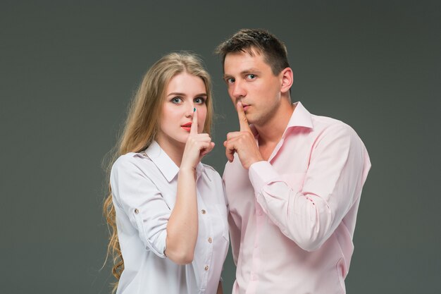 Portrait of a young couple standing against gray background