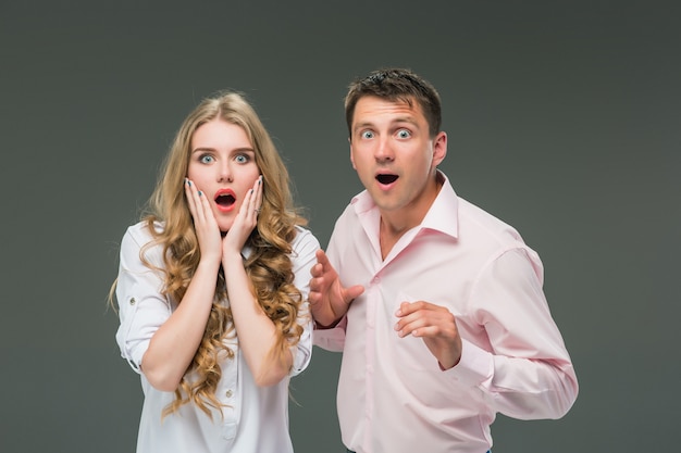 Portrait of a young couple standing against gray wall