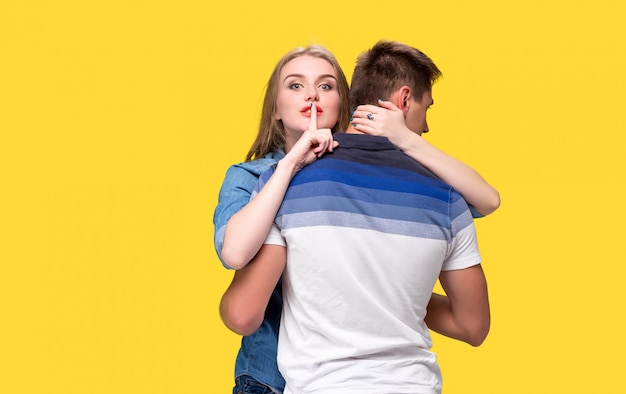 Free photo portrait of a young couple standing against yellow wall