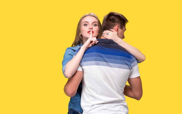 Portrait of a young couple standing against yellow wall