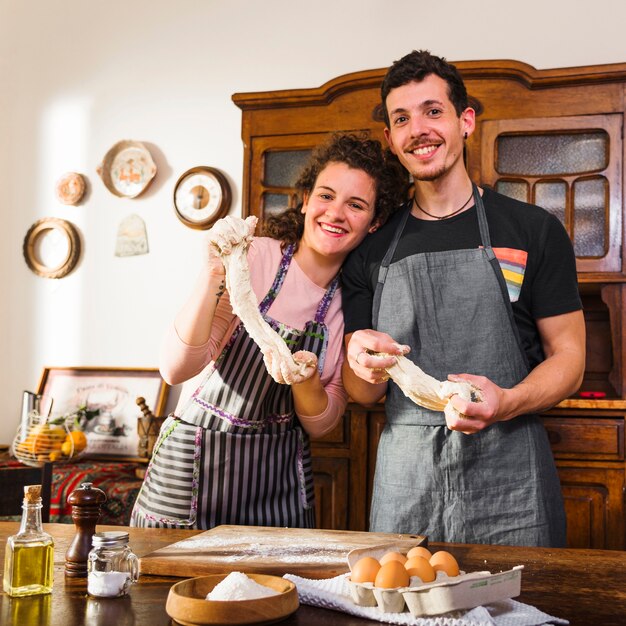 Portrait of young couple standing behind the table with baking ingredients on table