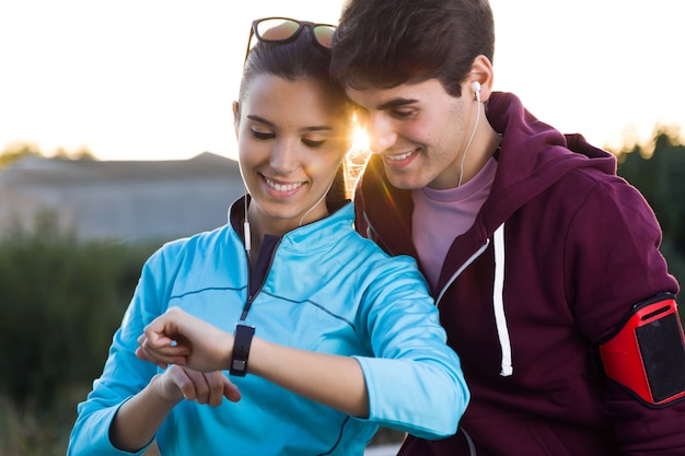 Портрет молодой пары, используя их smartwatch после запуска.