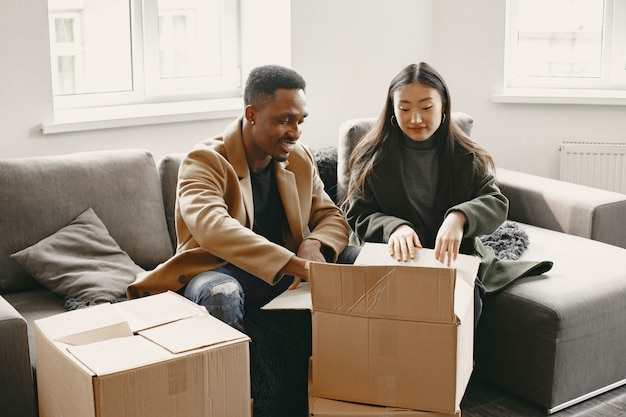 Portrait of young couple with cardboard boxes at new home, moving house concept.