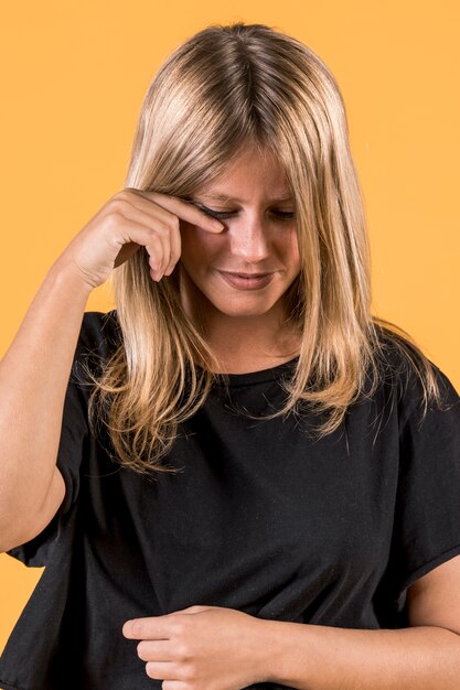 Portrait of young crying woman standing in front of yellow wall