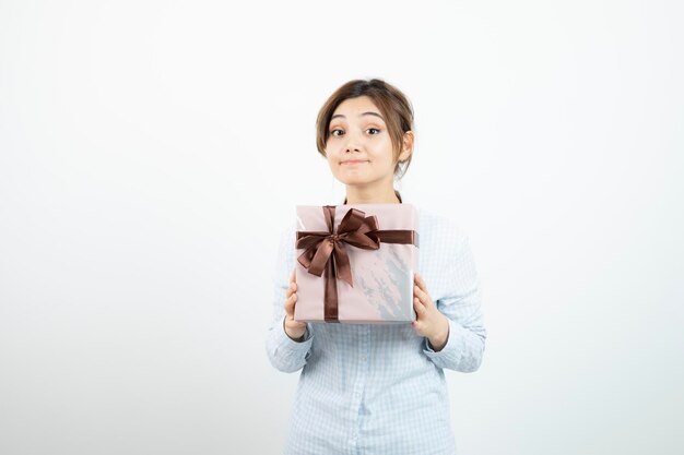 Портрет молодой милой девушки, держащей подарочную коробку с лентой. Фото высокого качества