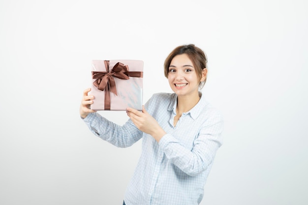 Portrait of a young cute girl holding present box with ribbon. High quality photo