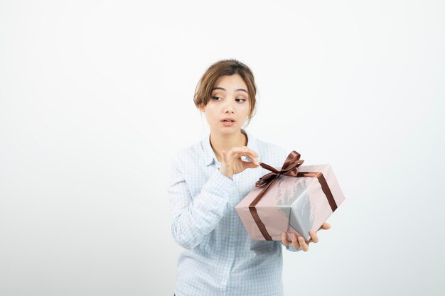 Portrait of a young cute girl holding present box with ribbon. High quality photo