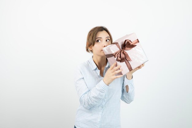 Portrait of a young cute girl holding present box with ribbon. High quality photo