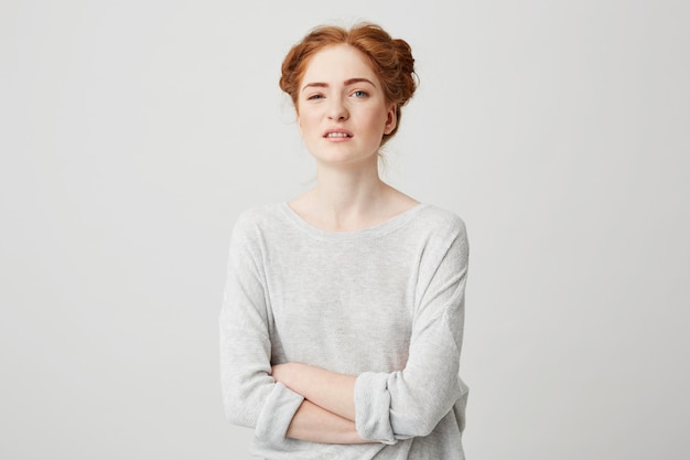 Portrait of young displeased ginger girl with crossed arms .