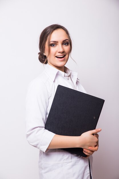 Portrait of young doctor or medic with clipboard and stethoscope isolated on white wall