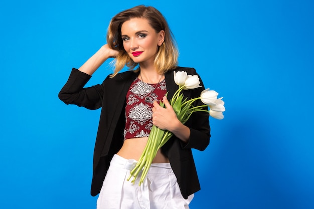 Portrait of young elegant woman with bright make up and dark blazer, holding white flowers