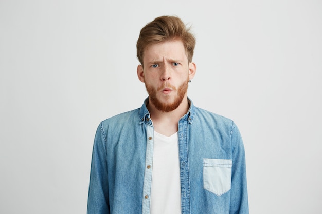 Portrait of young emotive shocked man frowning looking at camera.