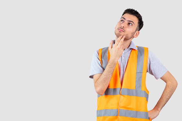 Portrait of young engineer in safety vest thinking something