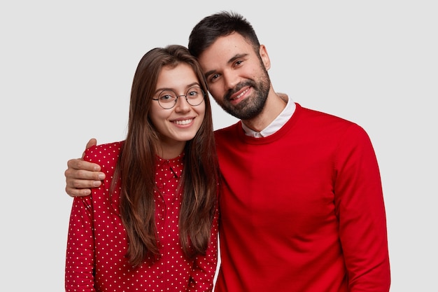 Portrait of young family European couple wear red clothes, pose for making common photo, have good relationships