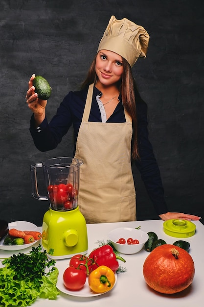 Free photo portrait of young female cook holds vegetables.