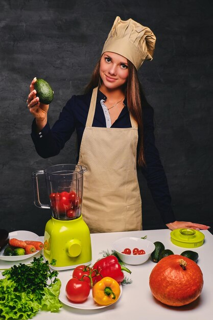 Portrait of young female cook holds vegetables.