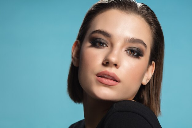 Portrait of young female fashion model isolated on blue  background.